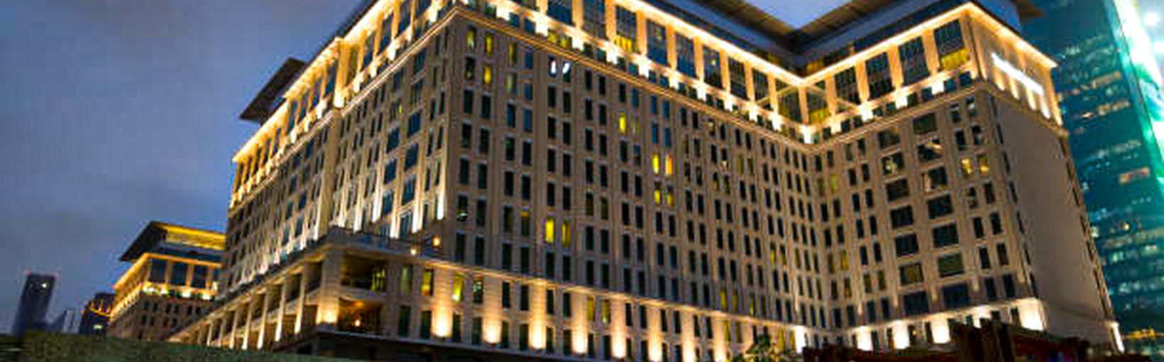 Die Außenfassade des Ritz-Carlton Hotels in der Abenddämmerung mit beleuchteter Beschilderung und Gebäudebeleuchtung.