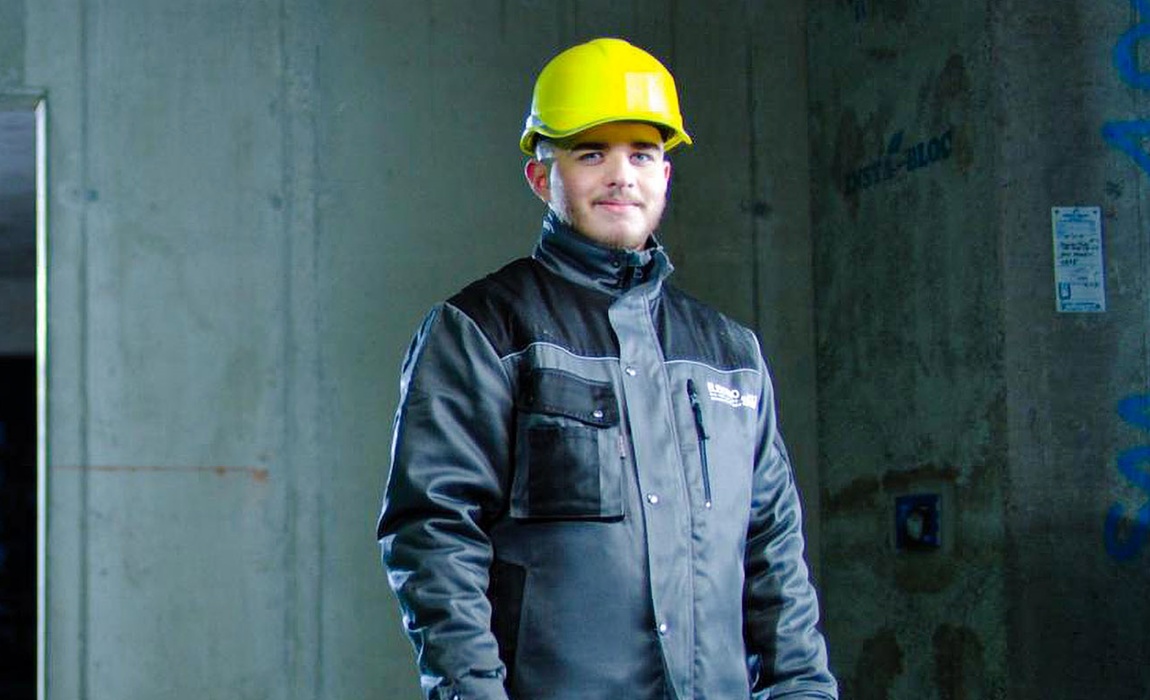 Mann mit gelbem Schutzhelm und Arbeitsjacke auf einer Baustelle im Haus.
