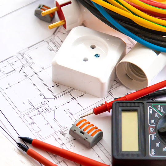 Elektrische Werkzeuge, Drähte und Steckdosen auf einem Bauplan oder einem Elektroplan.